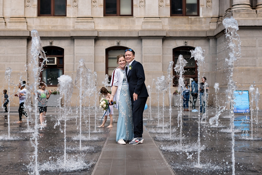 A groom and bride pose in the fountain at Dilworth Park in Philadelphia.